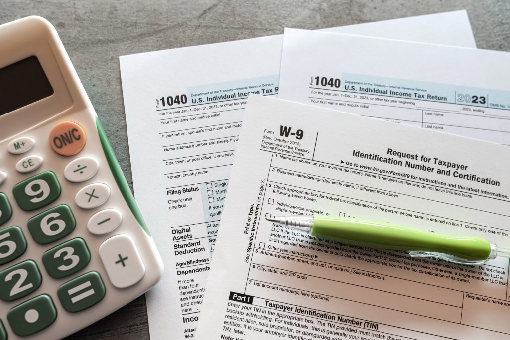 1040 US tax form with pen and calculator on office desk. Taxes burden